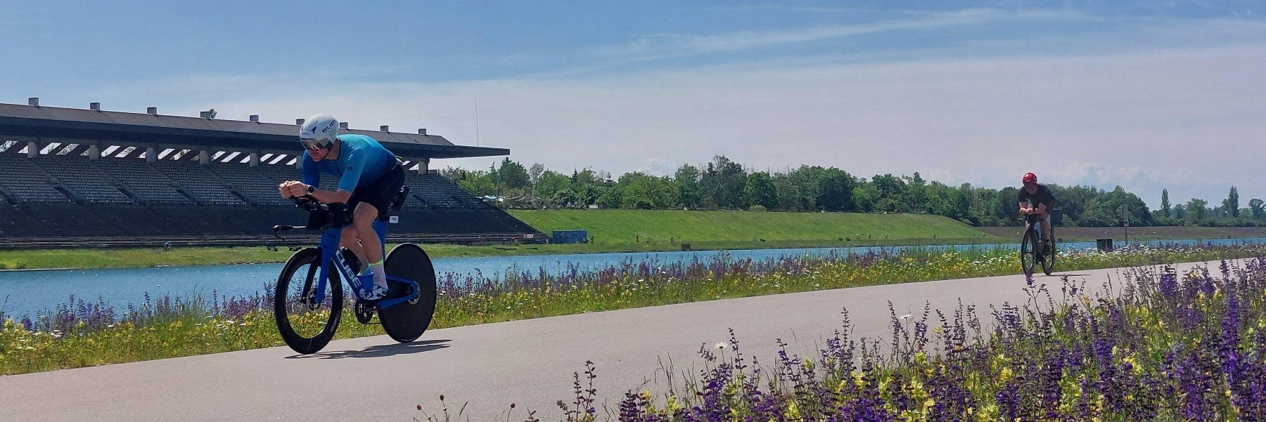 Zwei Triathleten hintereinander auf dem Rad in Zeitfahrposition entlang der Olympiaregattastrecke Oberschleißheim / München