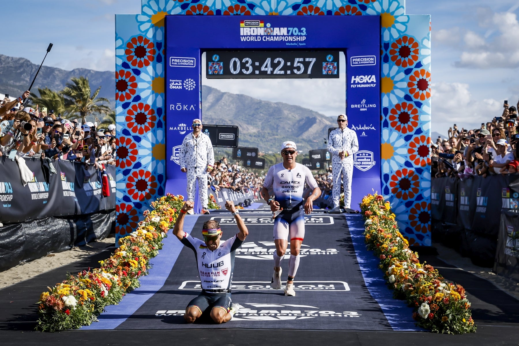 Im Ziel: Jelle Geens jubelt knieend wenige Meter hinter der Ziellienie, die Kristian Blummenfelt gerad durchläuft